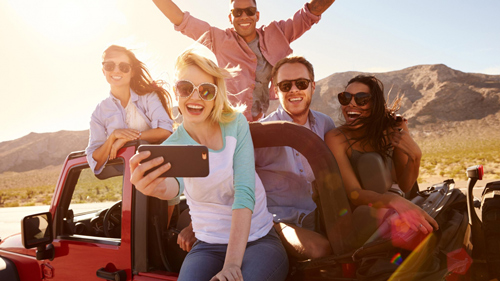 nhóm bạn 5 người đang cầm điện thoại selfie